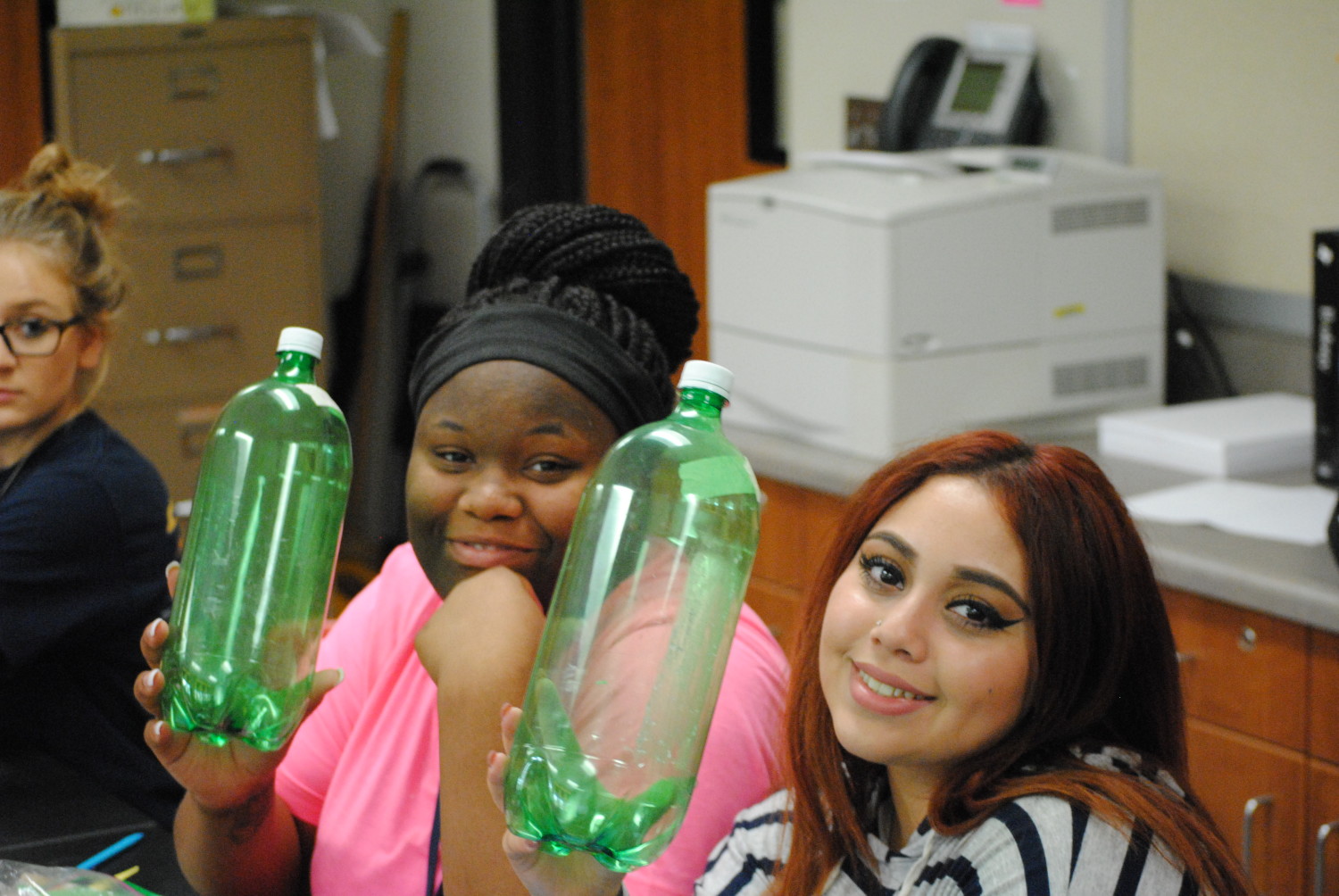 Hauke students hold up the bottles that they will make into rockets in physics class.