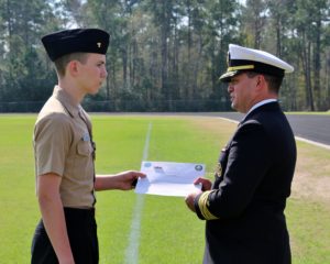 Cadet Chief Elijah Berger receives the Meritorious Achievement Ribbon from Captain Michael A. Carambas