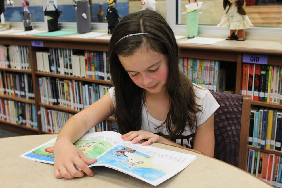 A Stewart Elementary fourth grader enjoys reading a book in the library.