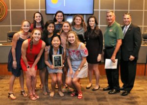 Nine girls' swim team members pose with their coaches and Board Member Ray Sanders in the CISD Board Room.