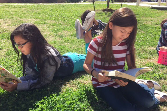 Travis students enjoy the beautiful weather and a good book.