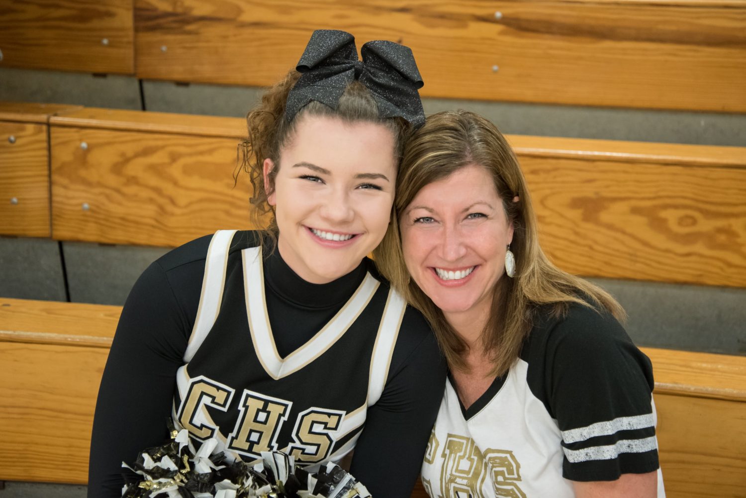 a cheerleader poses for a picture with her mom