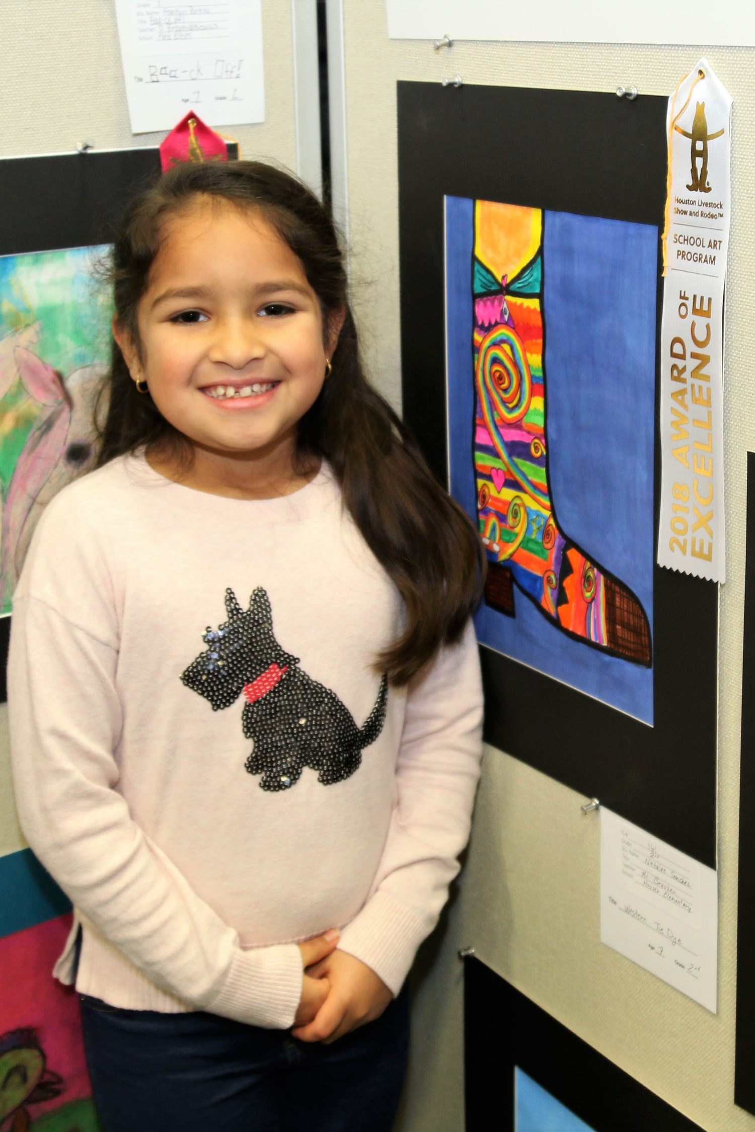 a girl stands next to artwork she created