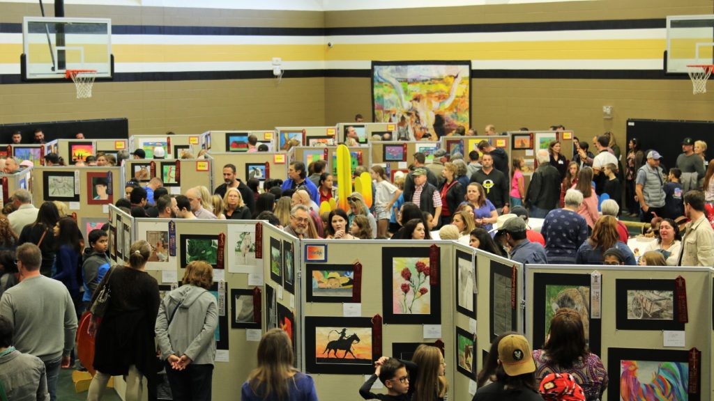 Participants at an art show in a school gym.