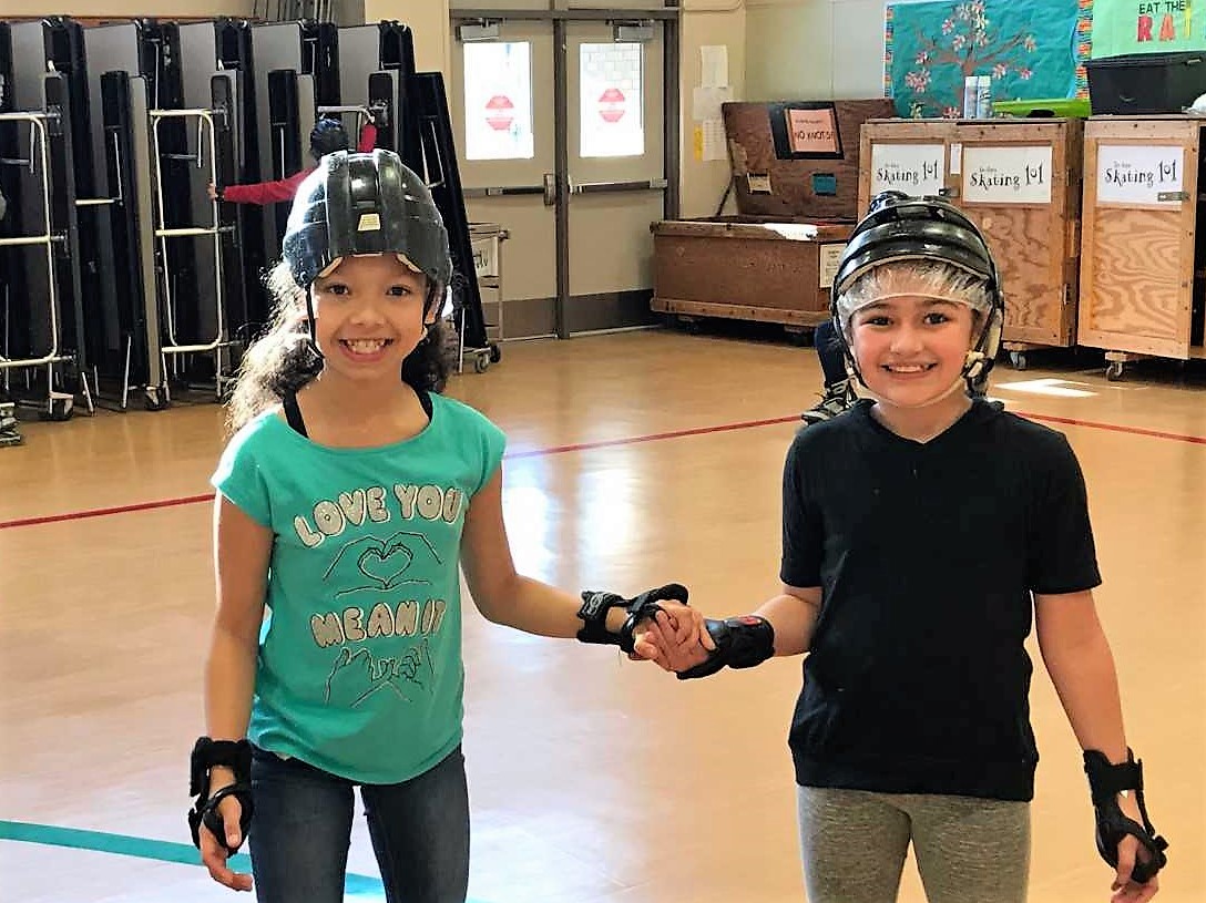 two girls pose for a picture while learning to roller skate