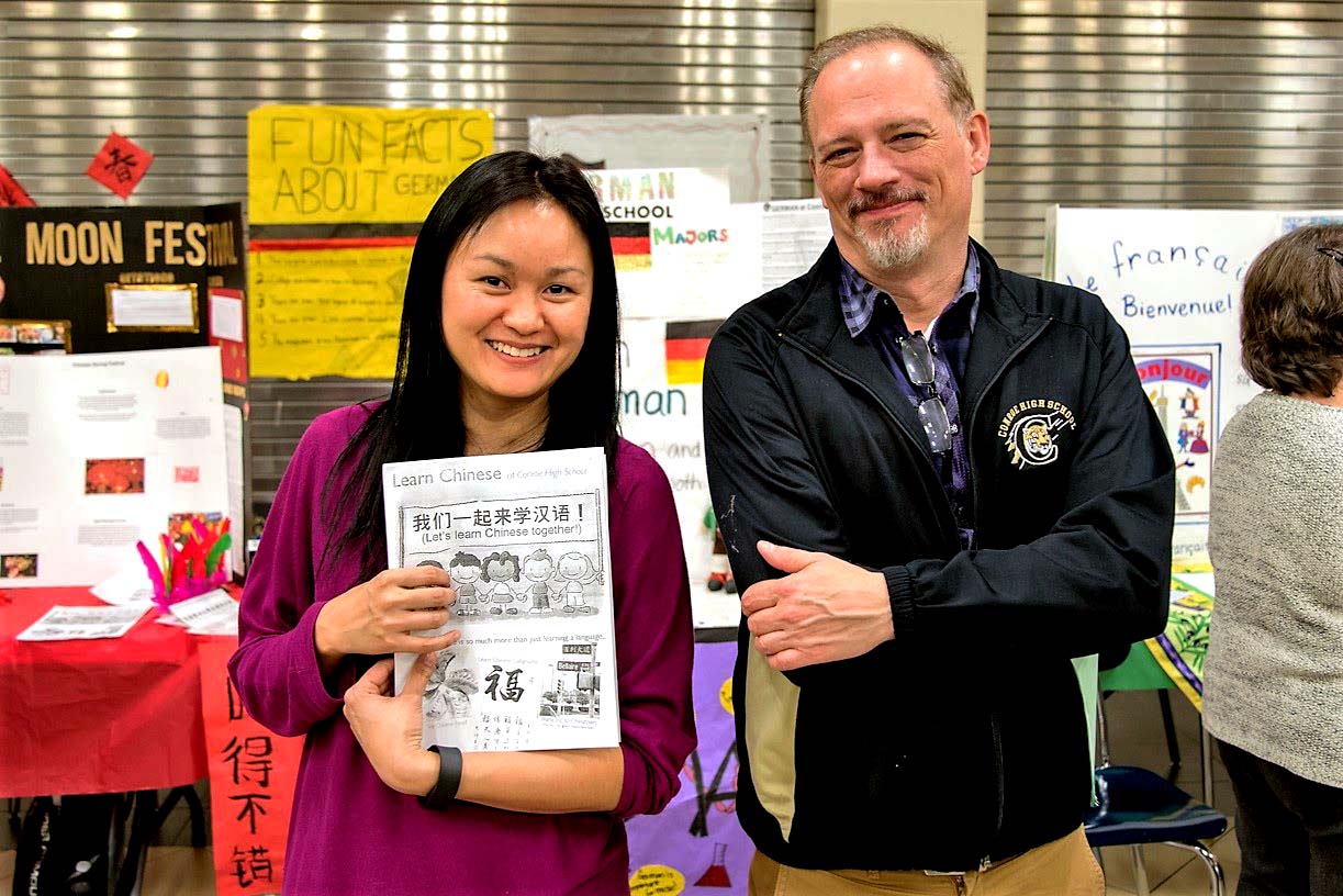 a student and a teacher hold up information on language courses