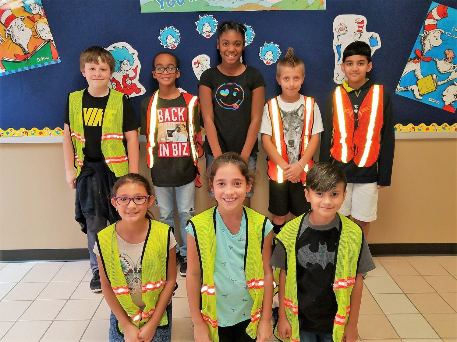 a safety patrol group of students wearing their safety yellow vests pose for a picture