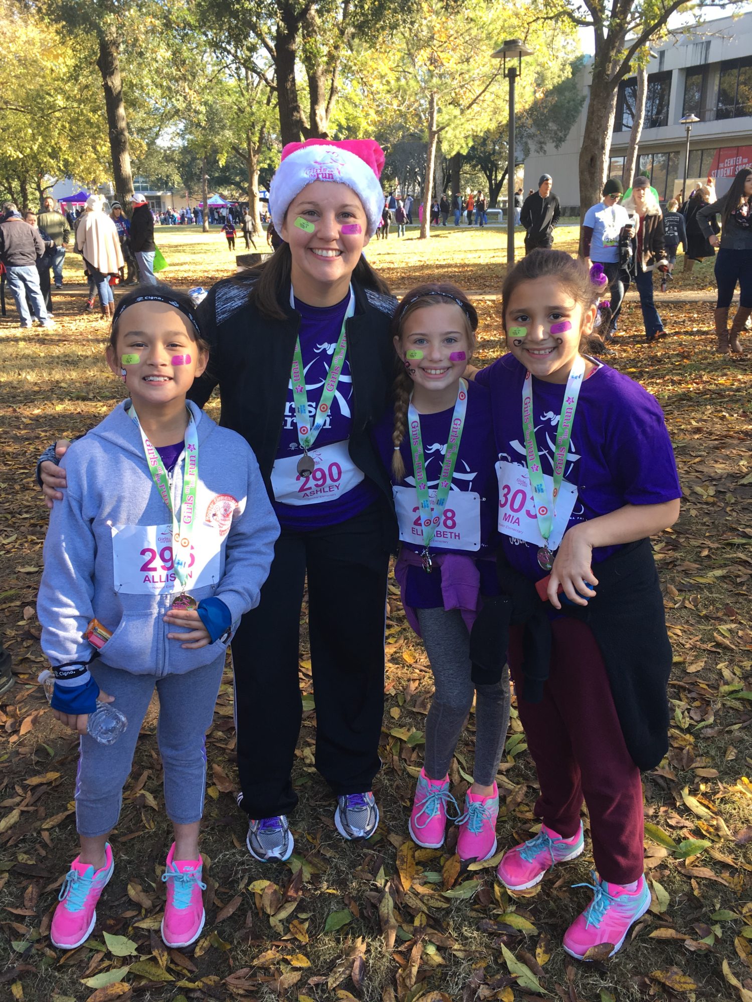 four girls pose with their running coach after completing a 5k run