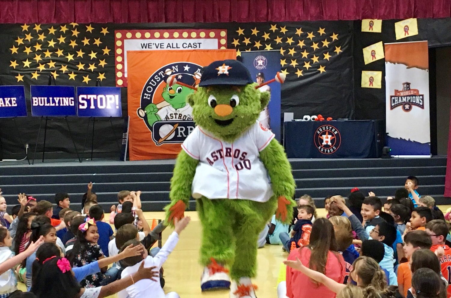 "a student assembly receives a visit from the Houston Astros mascot"