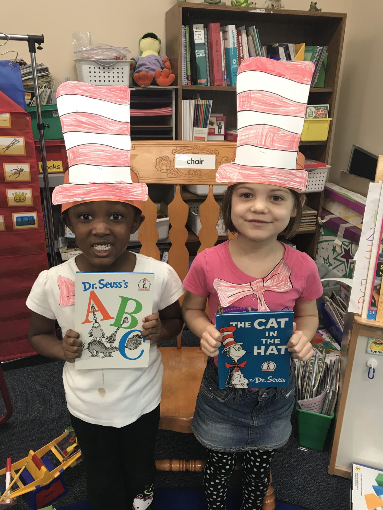 "two students pose with Dr. Seuss books and hats"