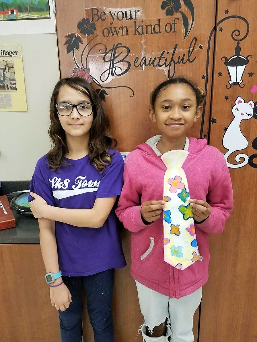 two girls display the art tie they created
