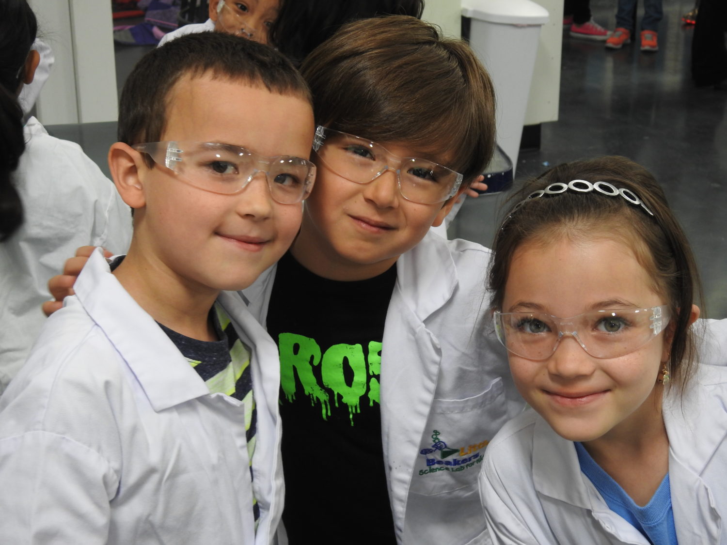 "a group of children wear science safety goggles"