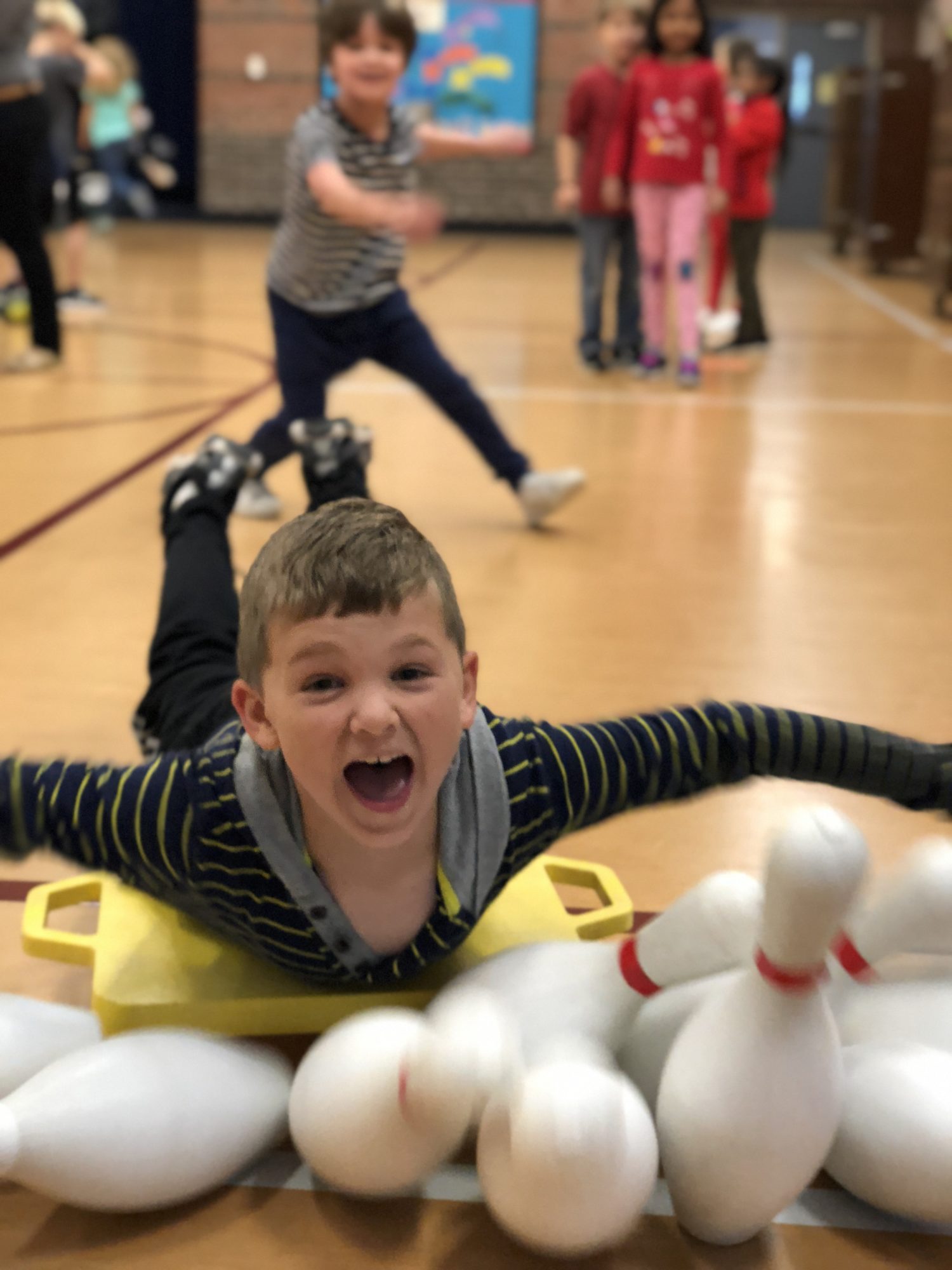 "a little boy smiles while playing human bowling"
