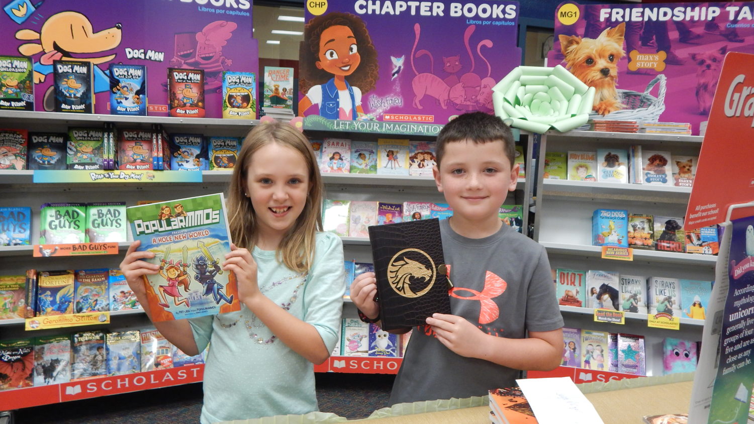 "two students hold up books from the book fair"