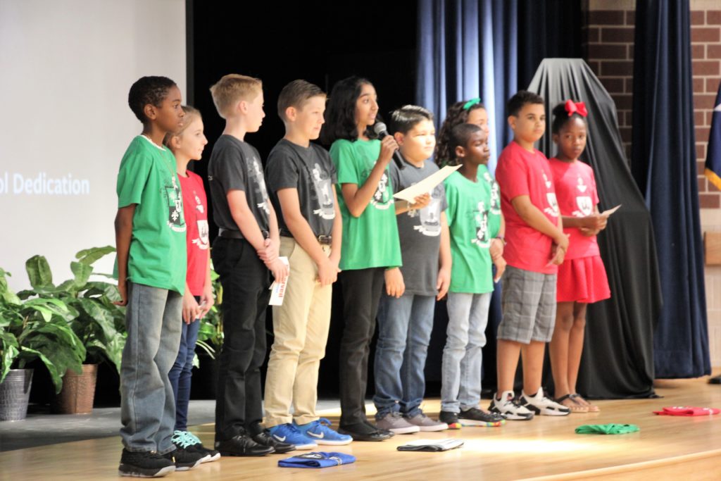 A diverse group of students make a presentation on a stage.