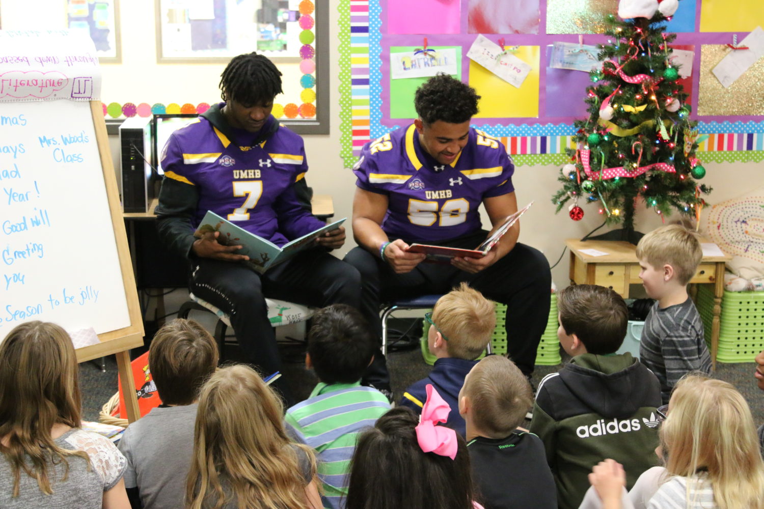 "two football players read to students"