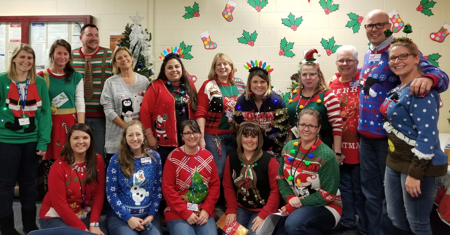 "a group of adults wear their ugly Christmas sweaters"