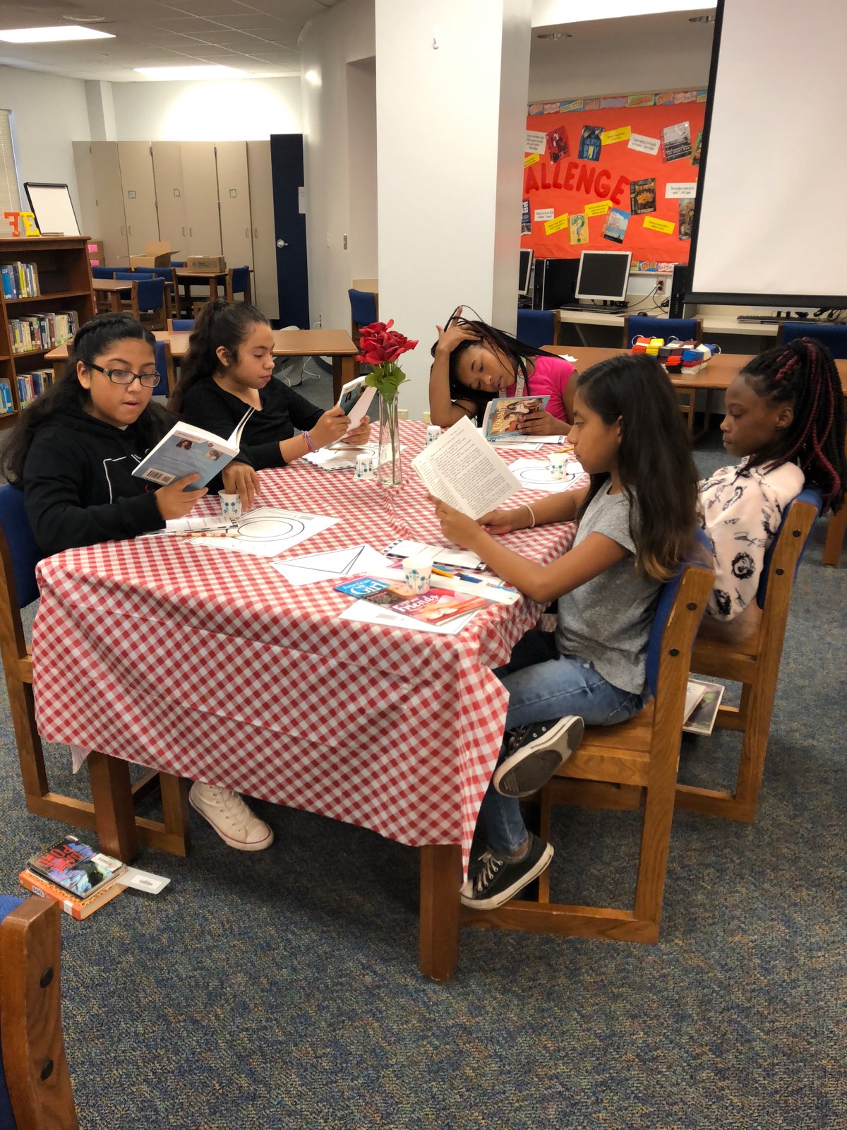 "four students sit at a table to read"