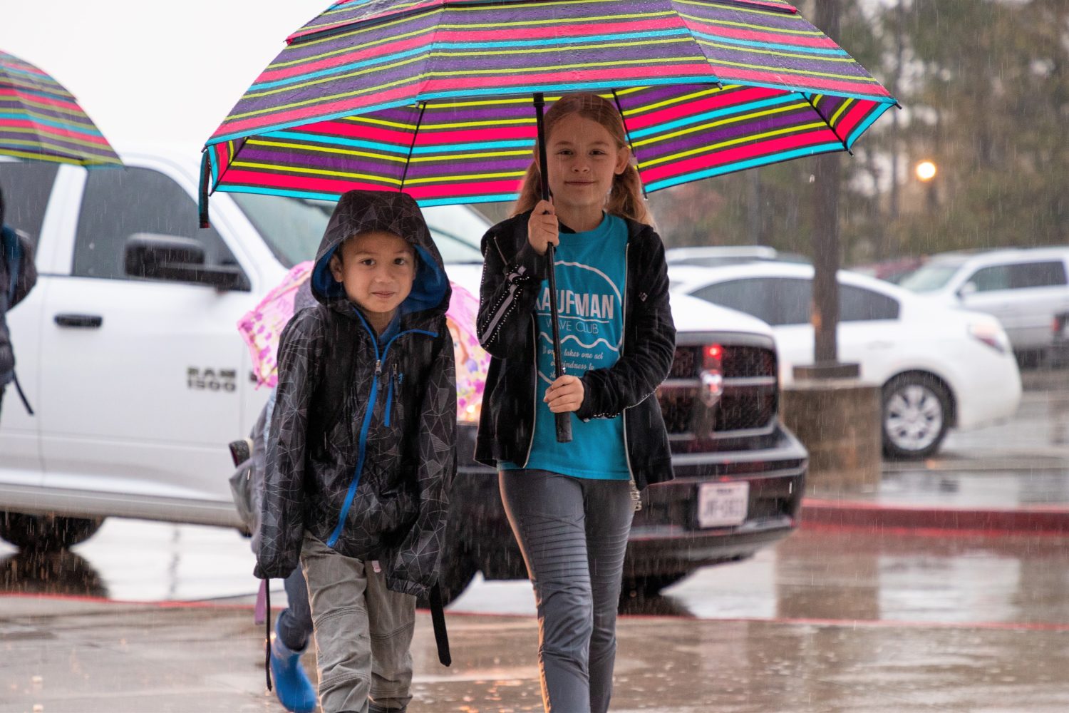 "two students walk under an umbrella"