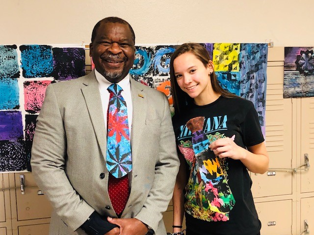 "a student poses with her art and school principal"