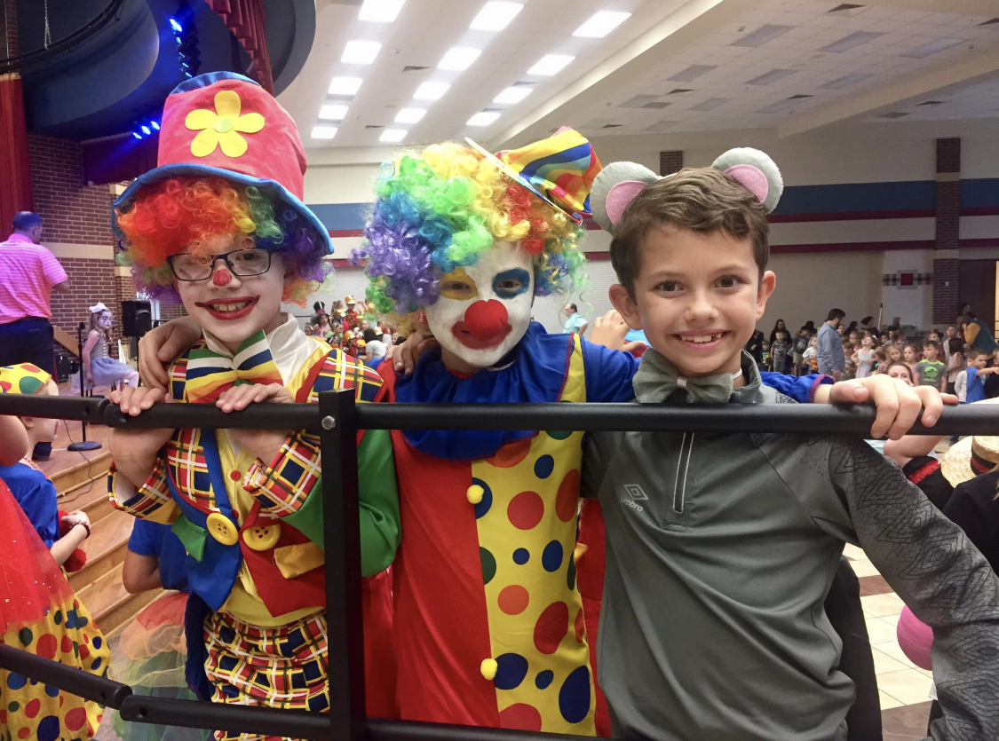 "three students dressed as clowns smile"