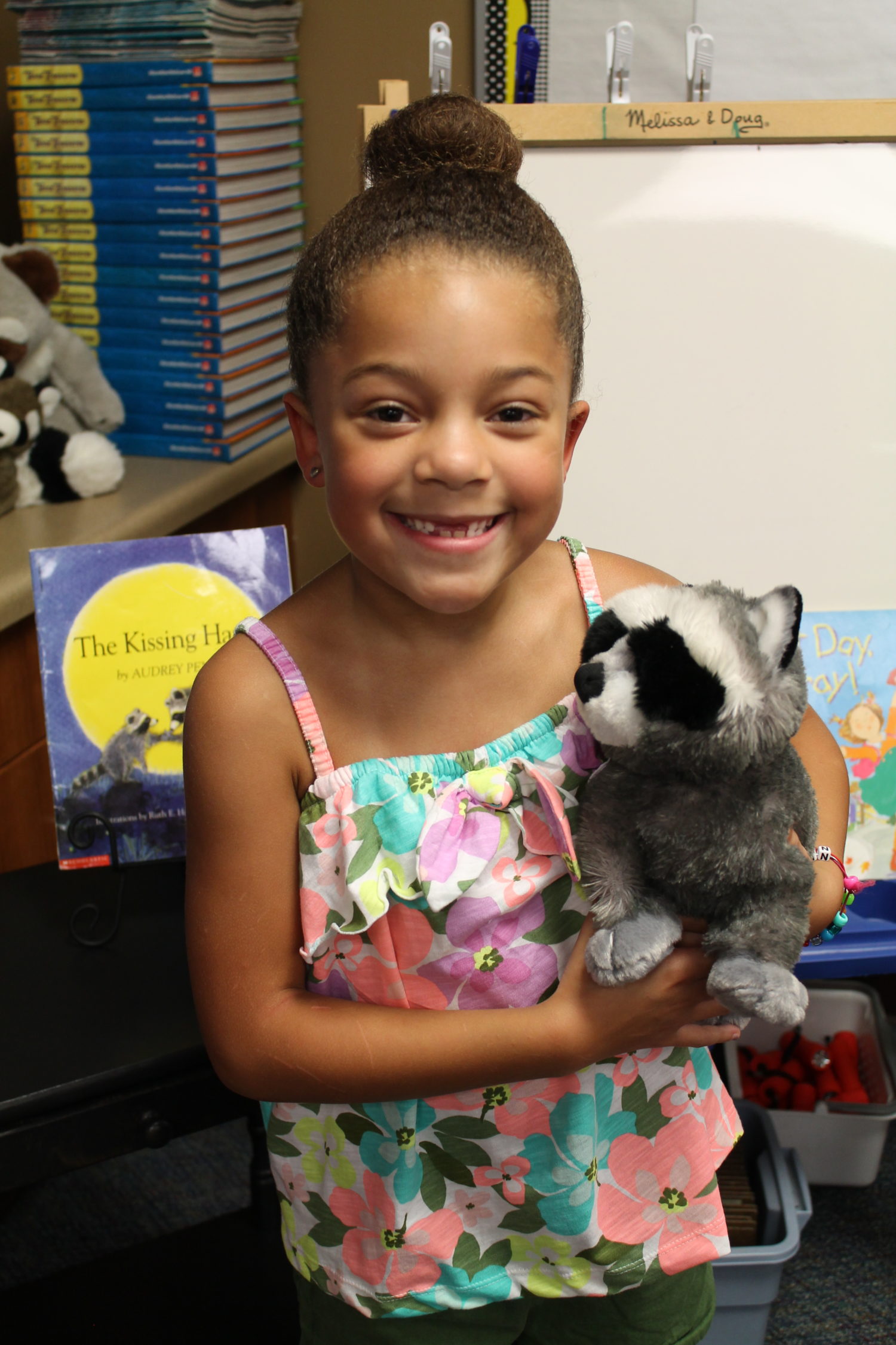 "a girl holds a stuffed animal raccoon"