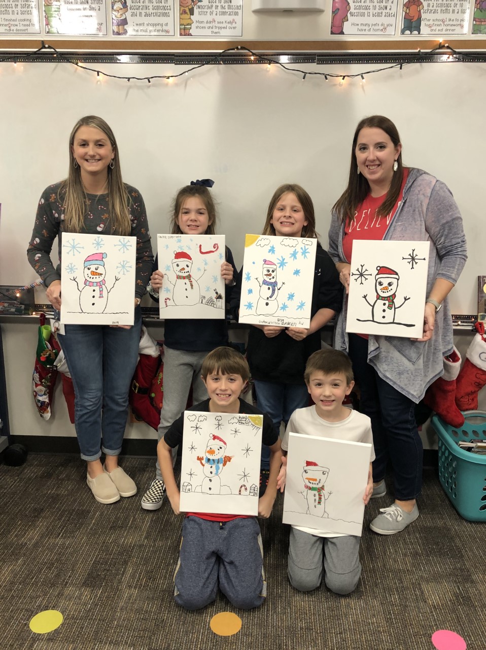 "teachers and students hold up their winter art creations"