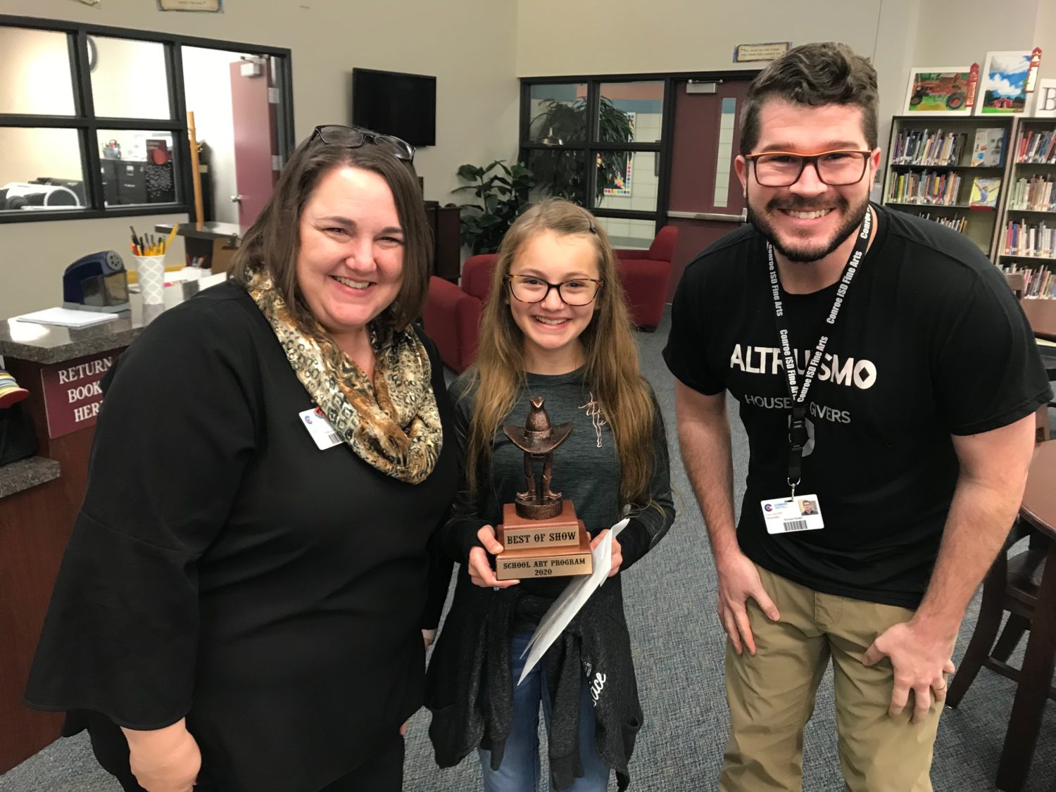 "a student holds her trophy while posing for a picture with two adults"