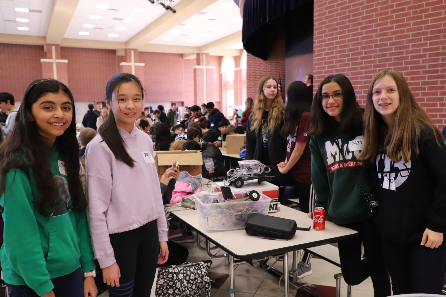 "four students with robotic components stand at a table"