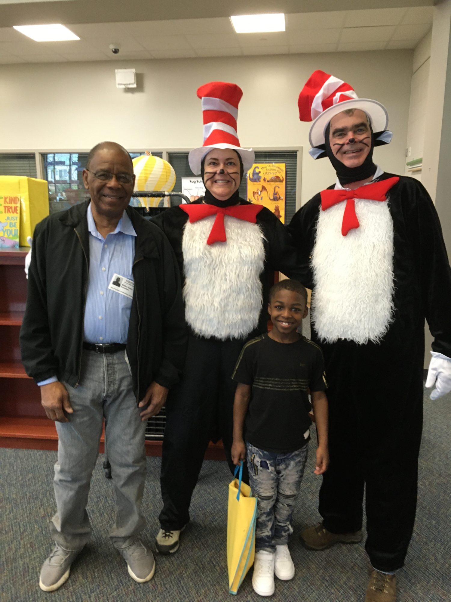"two adults dressed like Cat in the Hat pose with a child and an adult"