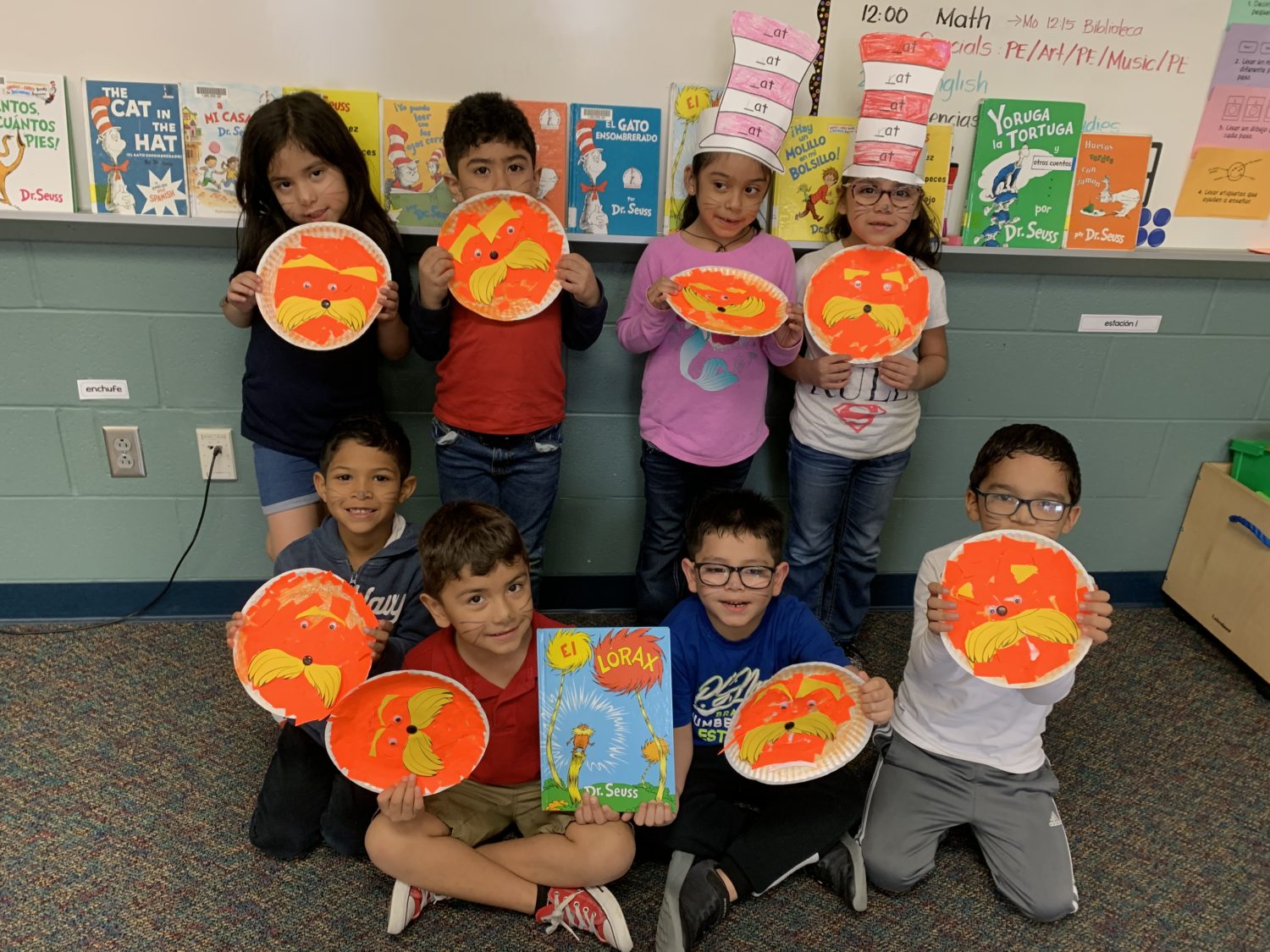 "students hold up their brightly colored Lorax paperplates"