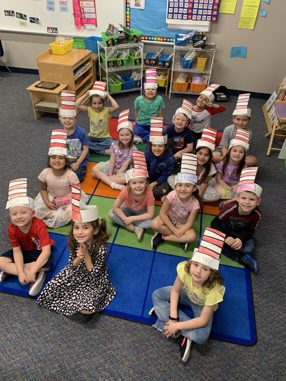 "a class sits on a rug while wearing their cat in the hat hats"