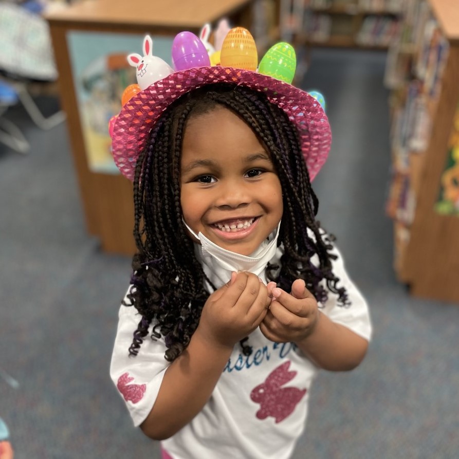 A student smiles for the camera while wearing an Easter hat.