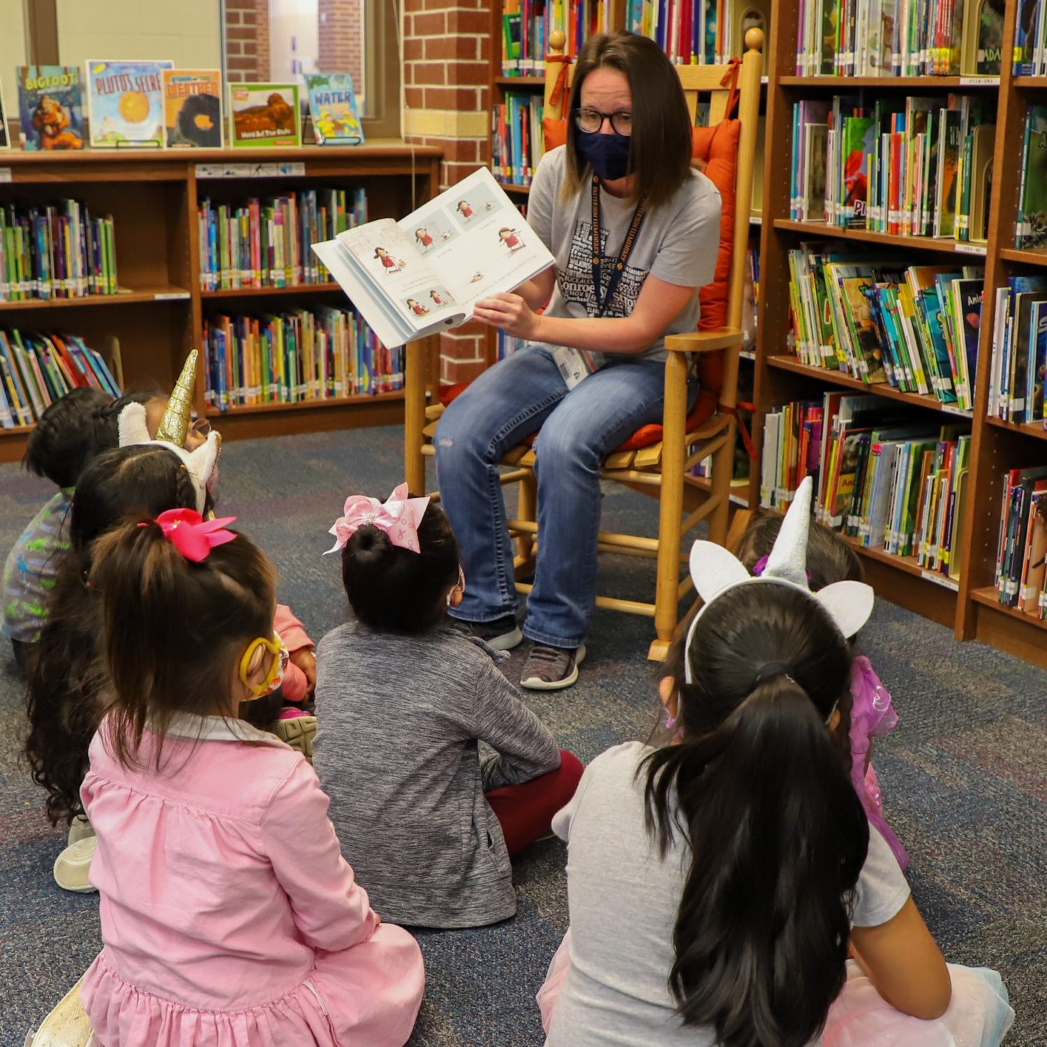 A librarian reads a book to a group of students.