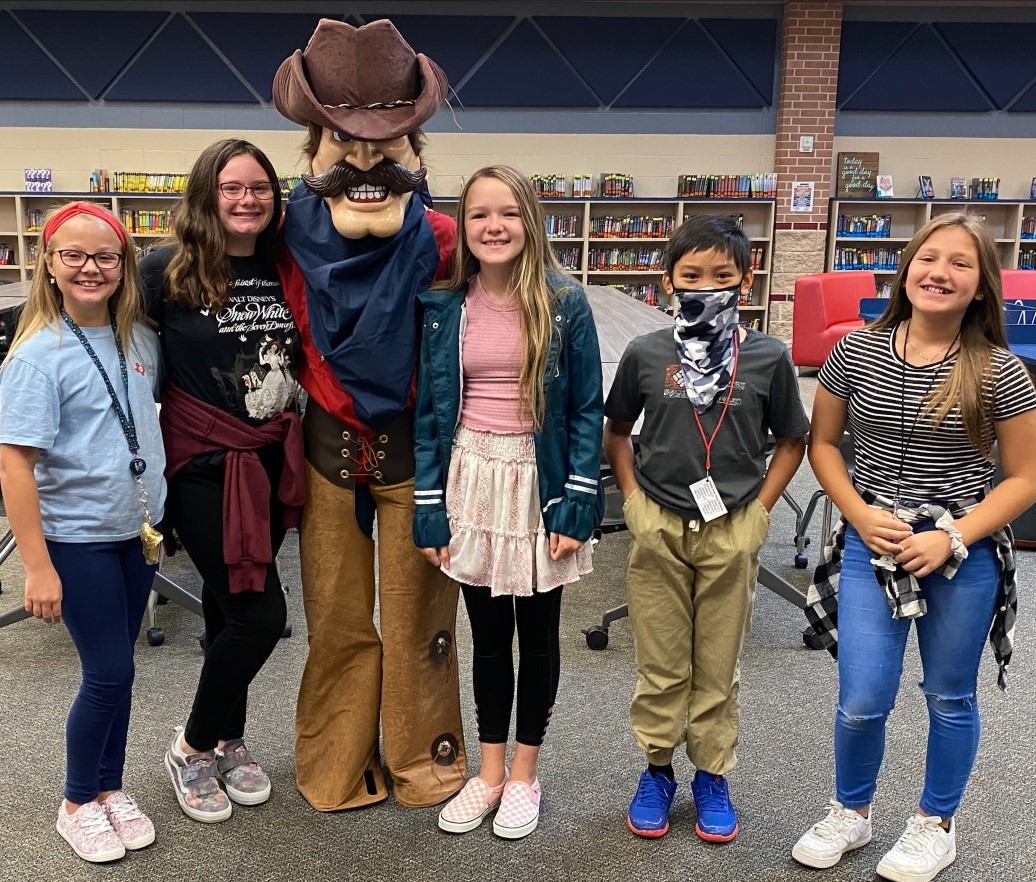 A group of students smiles while standing with their school mascot.