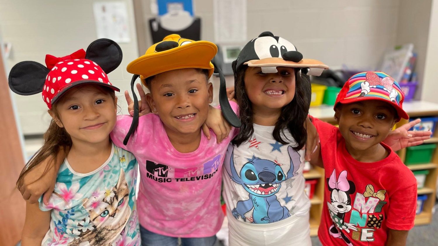 Four students smile while wearing fun hats.