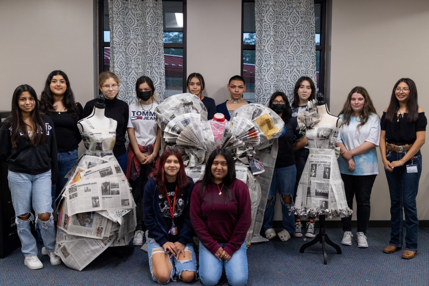 Students smile for the camera with newspaper dresses.