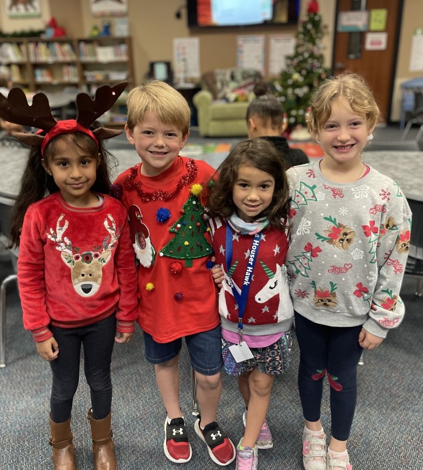 Students smile for the camera while wearing holiday sweaters.
