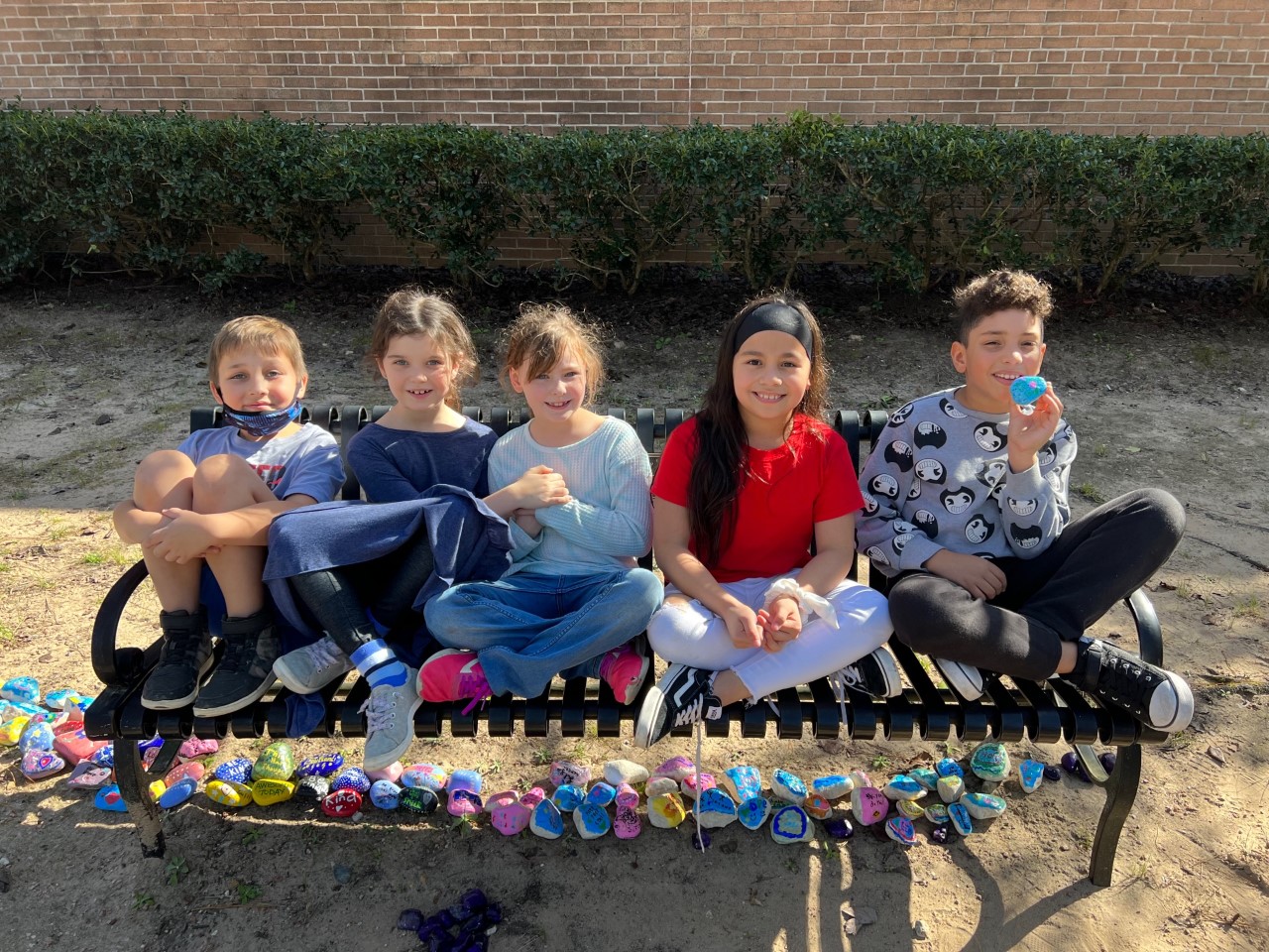 A group of students smile with their kindness rocks.