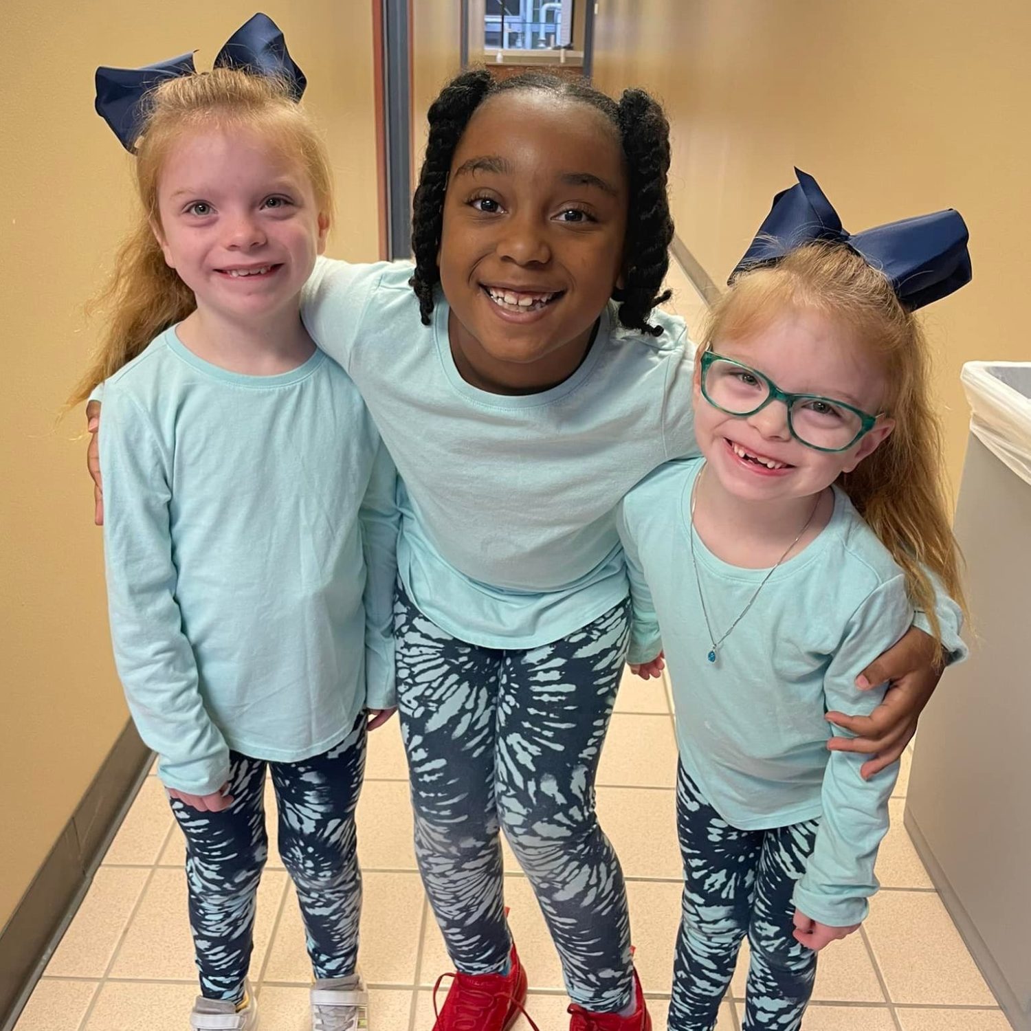Three students smile for the camera while wearing matching outfits.
