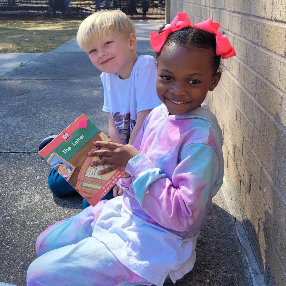 Two students read together outside.