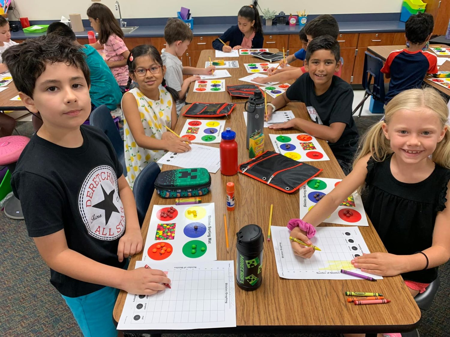 Students smile while practicing sorting skills with colorful candies!