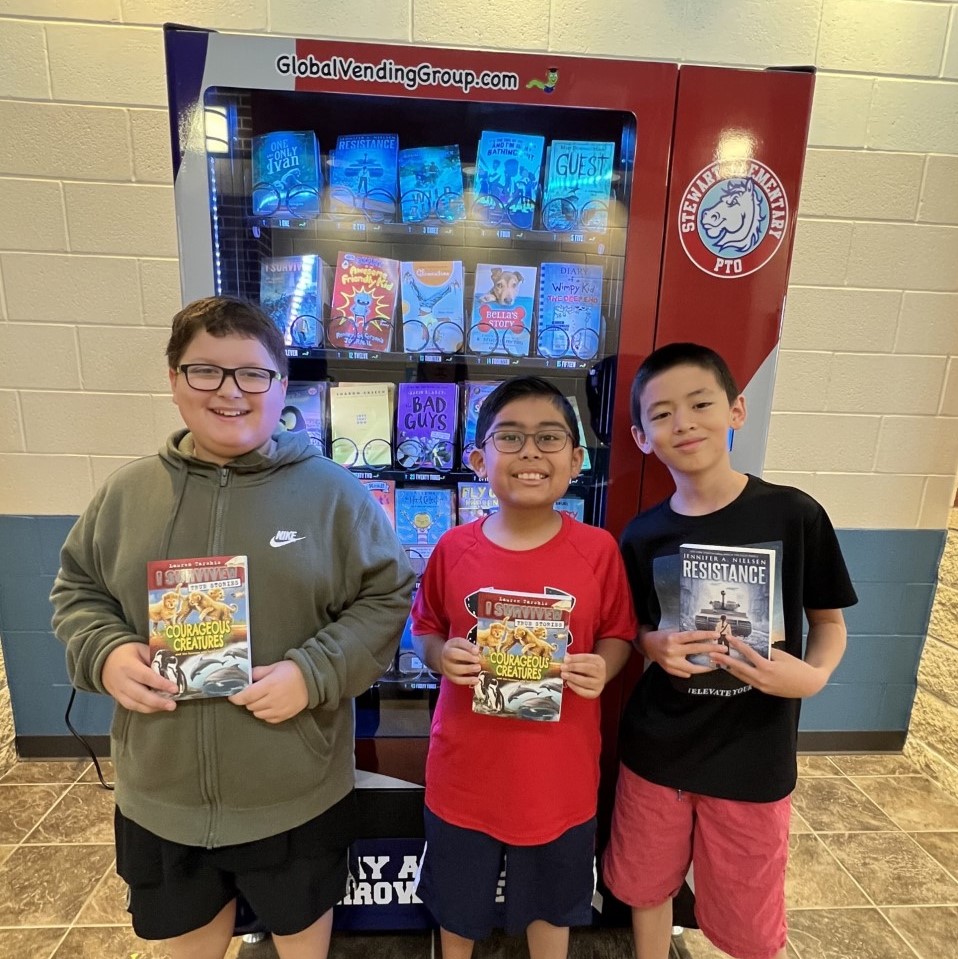 Students at Stewart smile in front of the book vending machine.