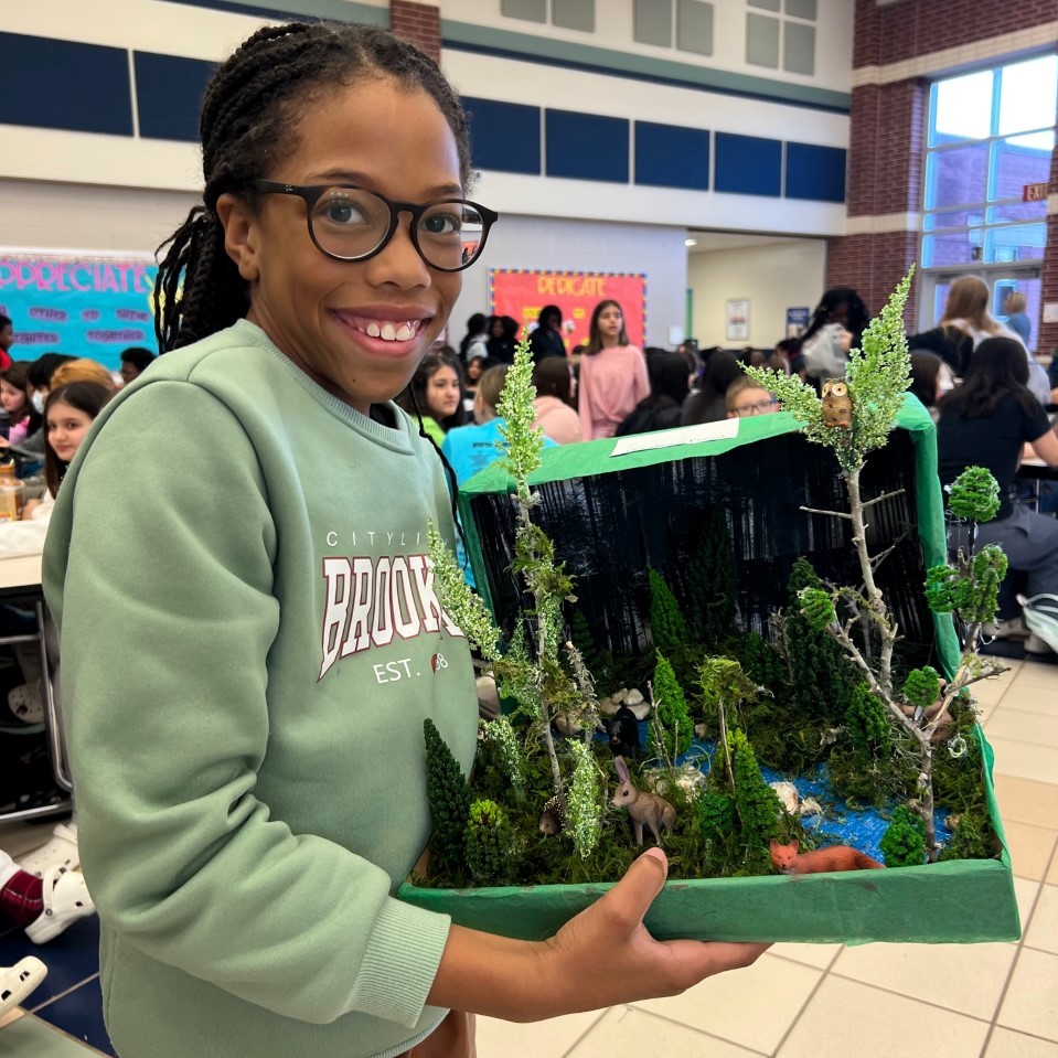 A Student at Cox smiles with their ecosystem project!