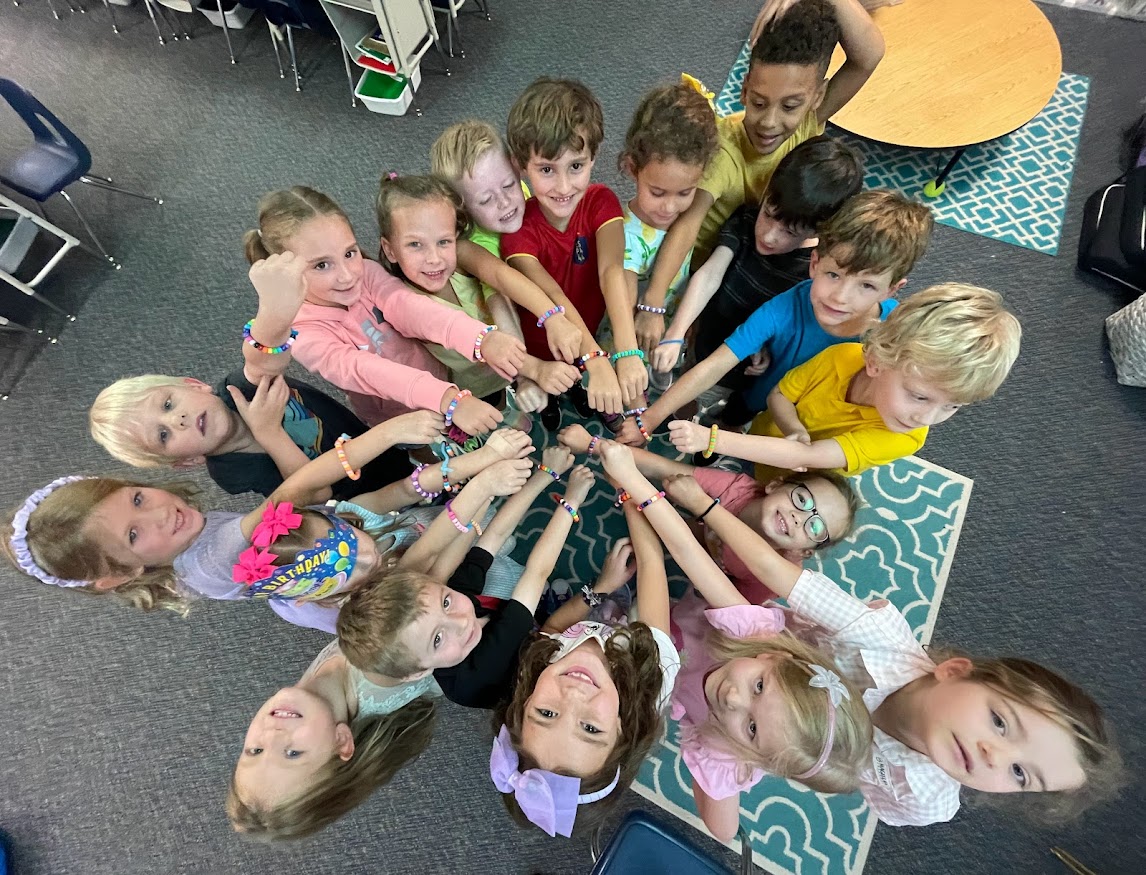 Students in a huddle showing off their friendship bracelets