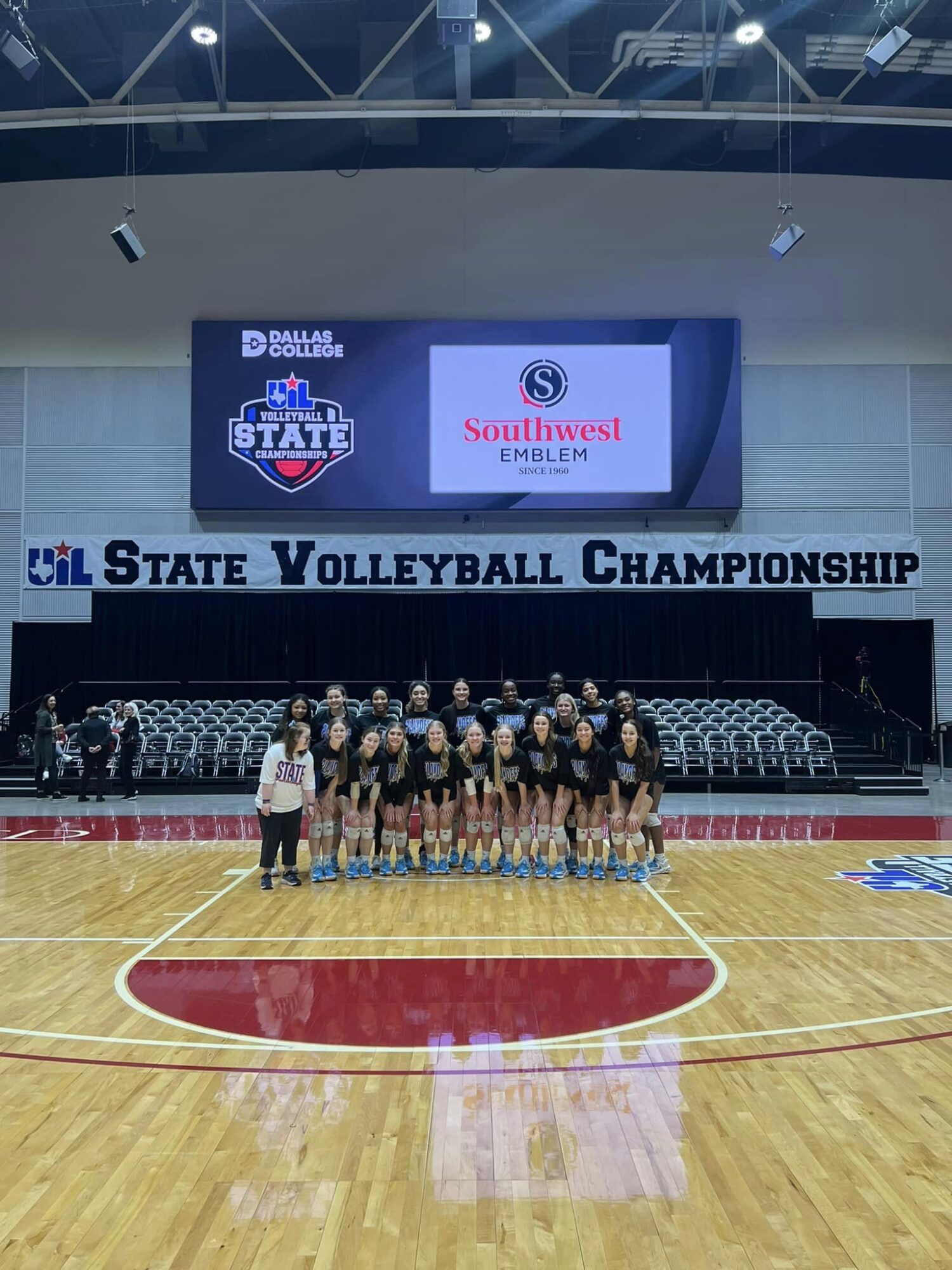 The Grand Oaks High School Volleyball Team poses in a gym with the State Volleyball Championship banner in the background.