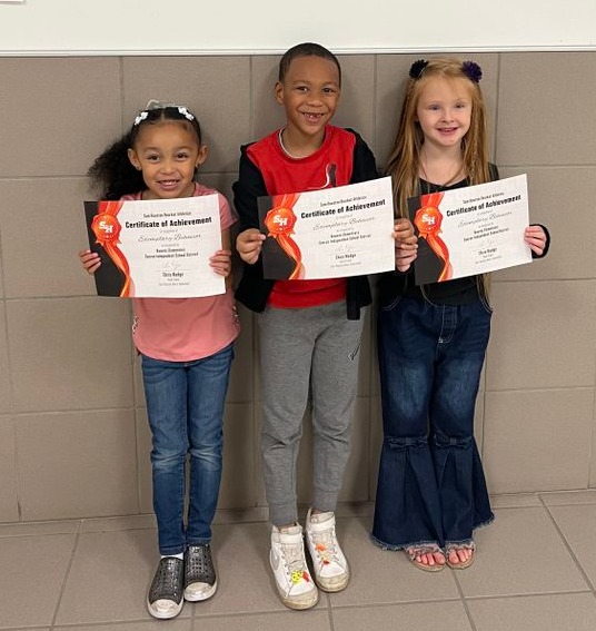 Three students holding up certificates for excellent behavior.